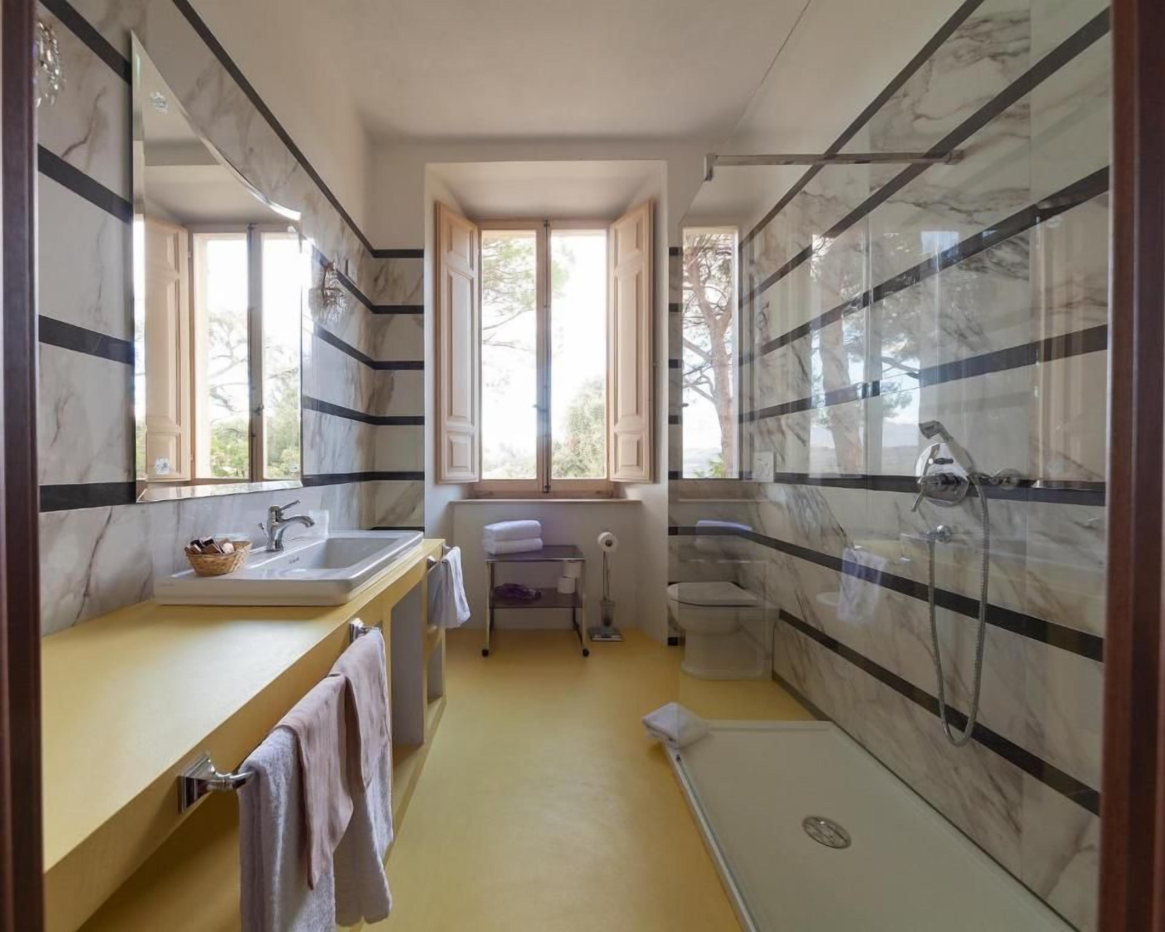 A bathroom with a bathtub, a shower, a sink, and a toilet. There is a window providing natural light.