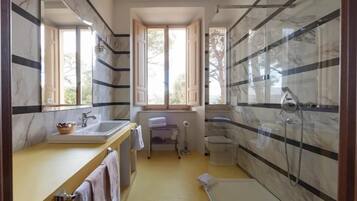 A bathroom with a bathtub, a shower, a sink, and a toilet. There is a window providing natural light.