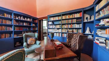 Eine Bibliothek mit Bücherregalen, einem Holztisch, zwei Stühlen und einer Zierdevas.
