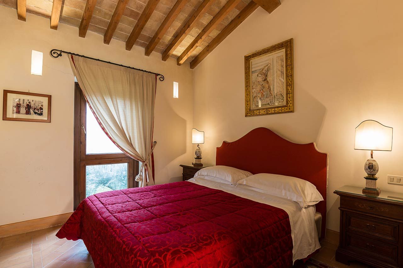 Quarto com uma cama grande, duas mesas de cabeceira com luminárias, uma janela com cortinas e um quadro na parede.