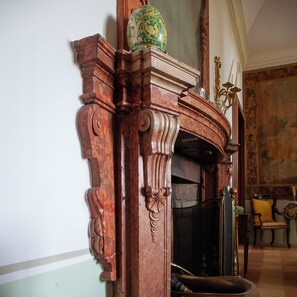 Una chimenea de madera detallada con tallas elaboradas y una jarra decorativa encima.