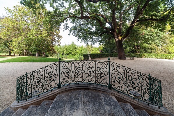 Un puente de piedra con barandillas de metal ornamentadas en un parque.