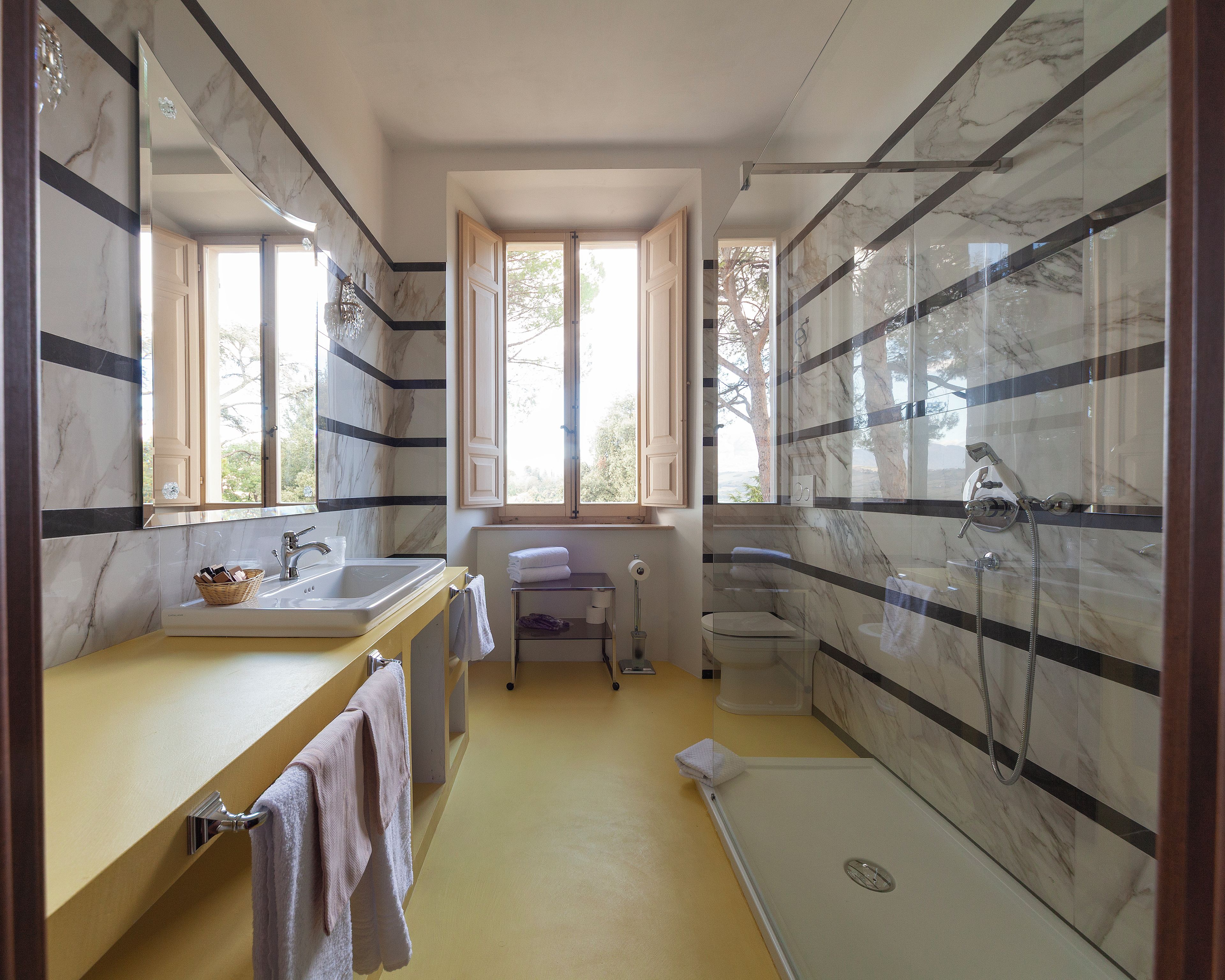 Une salle de bain avec une douche en marbre, un lavabo et une fenêtre.