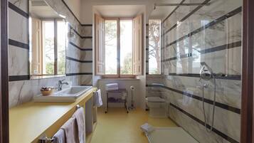 Une salle de bain avec une douche en marbre, un lavabo et une fenêtre.