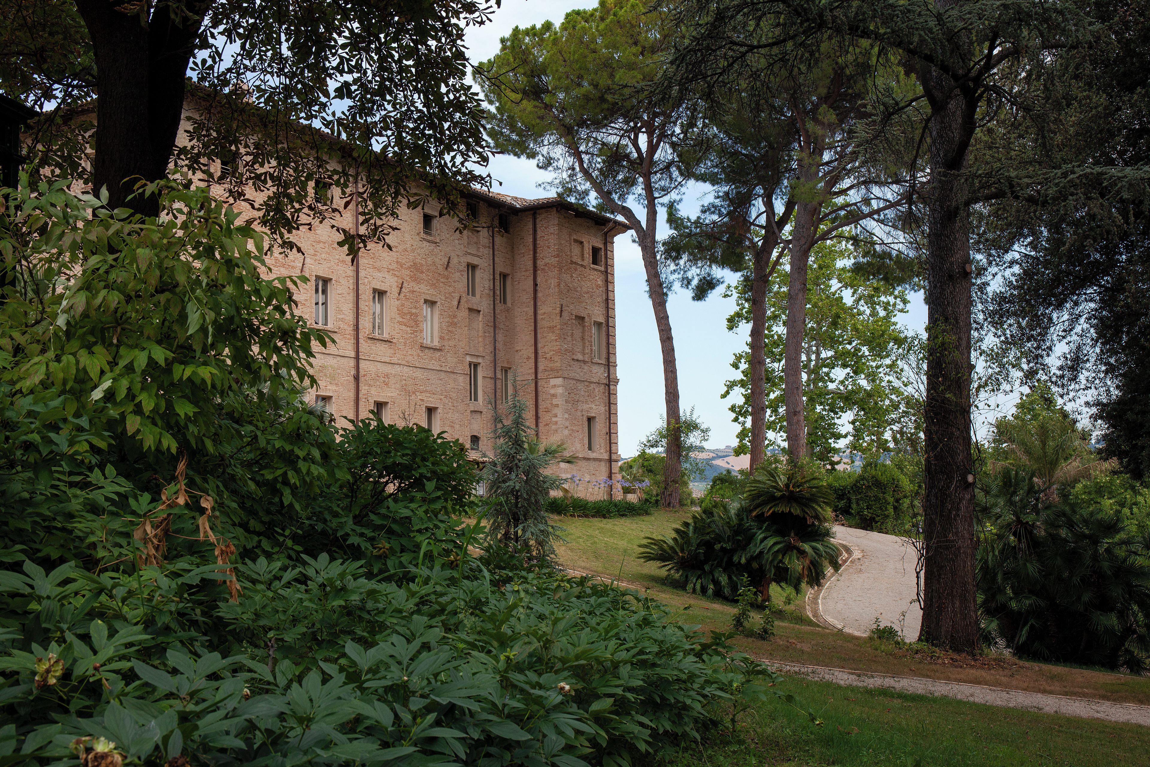 A brick building with a garden in front, surrounded by trees.