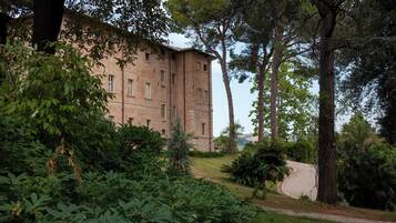 A brick building with a garden in front, surrounded by trees.