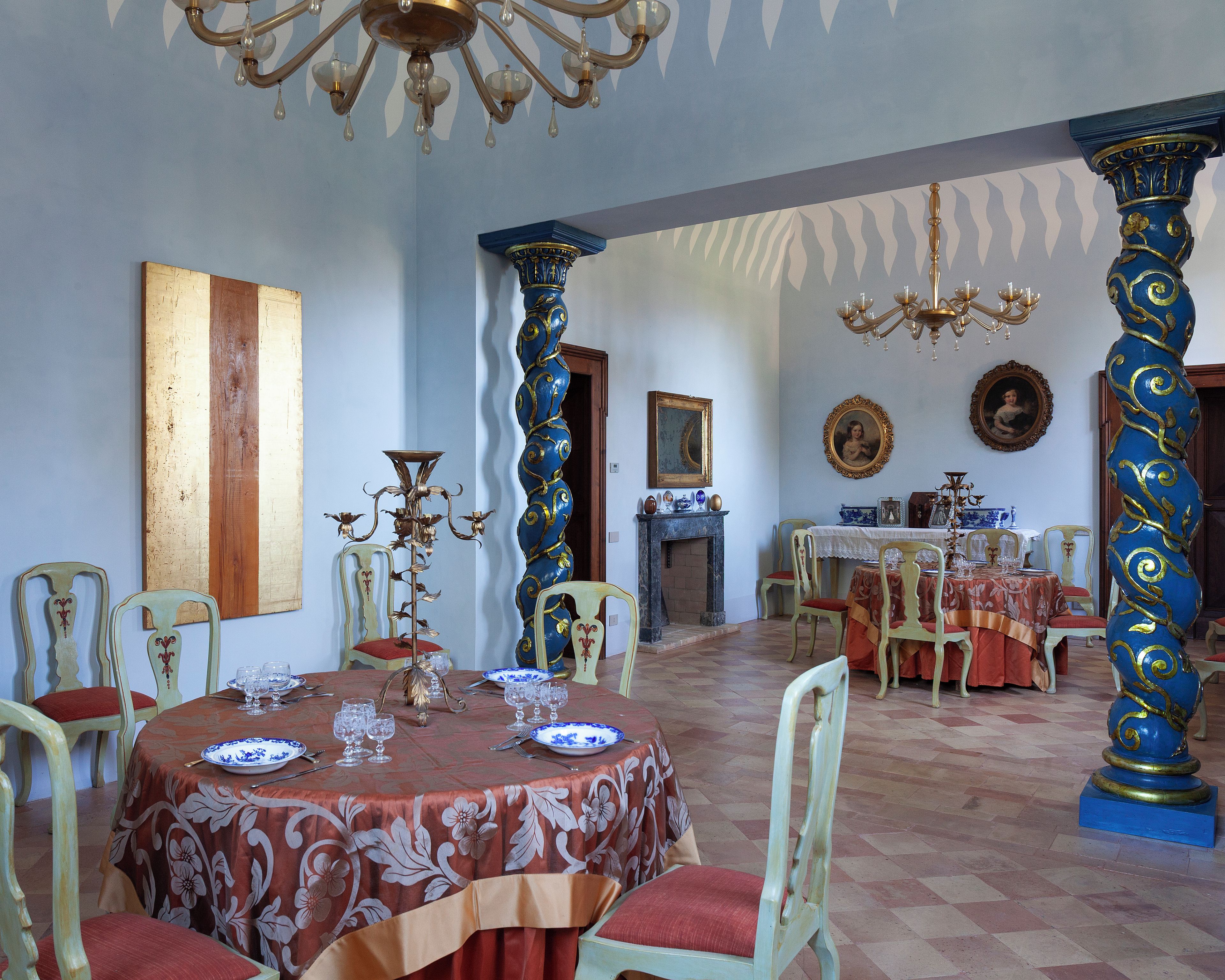 Un comedor con columnas ornamentales, chimenea y una mesa dispuesta para una comida.