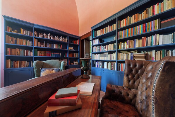 Une bibliothèque avec des étagères remplies de livres, un bureau en bois et un fauteuil en cuir.