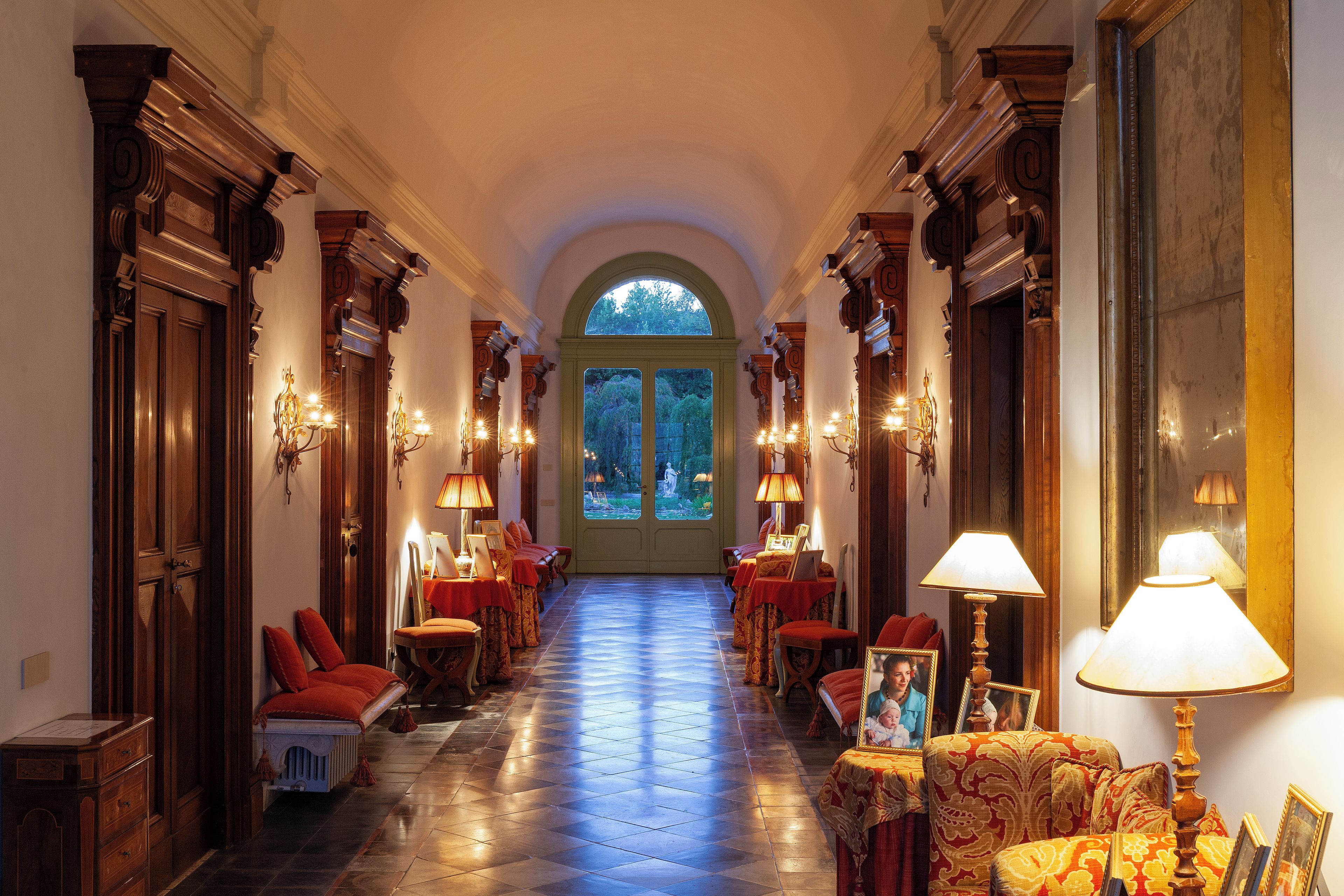 A hallway with a tiled floor, wooden doors, and a large arched window.