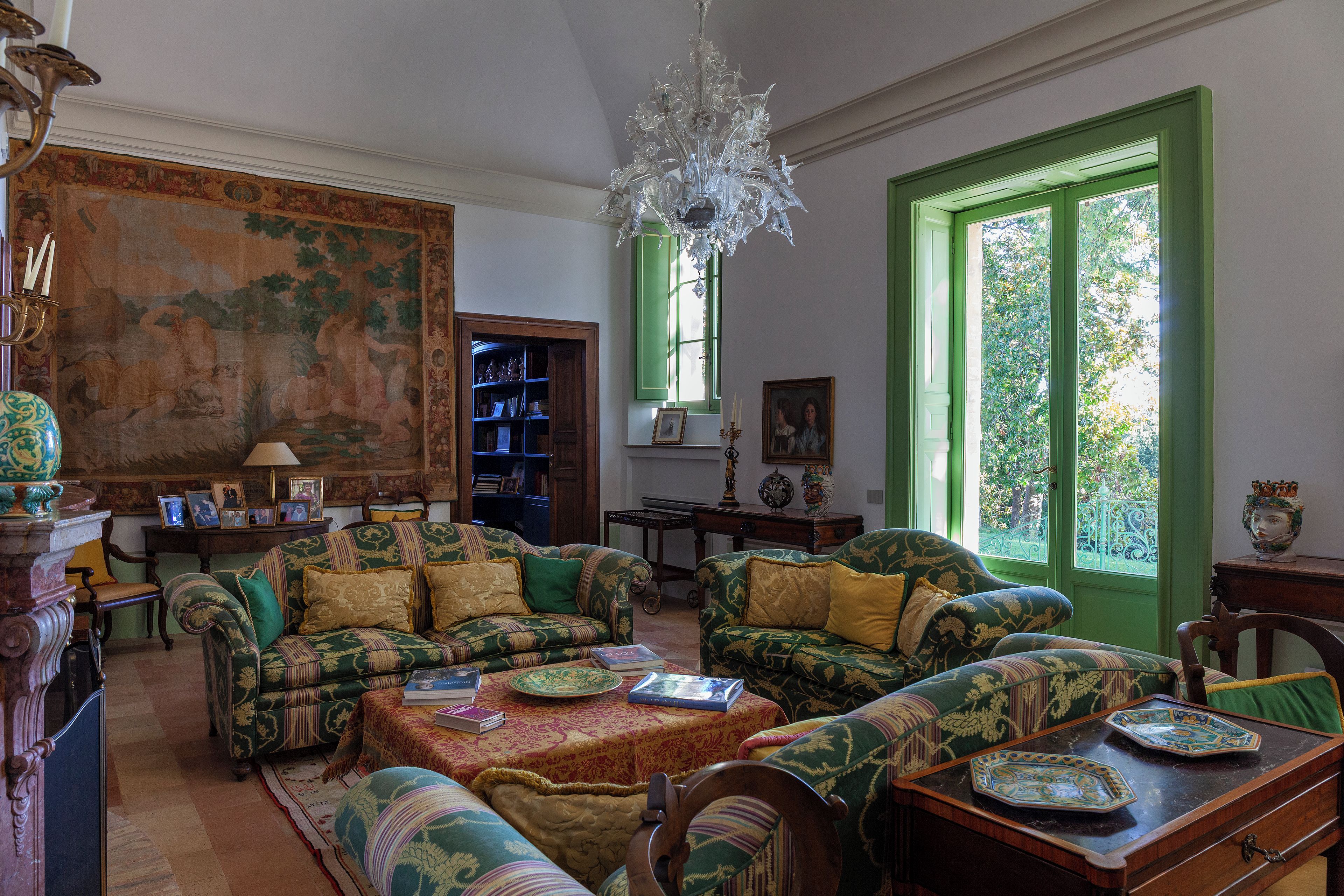 A traditional room with patterned furniture, a chandelier, and a green door.
