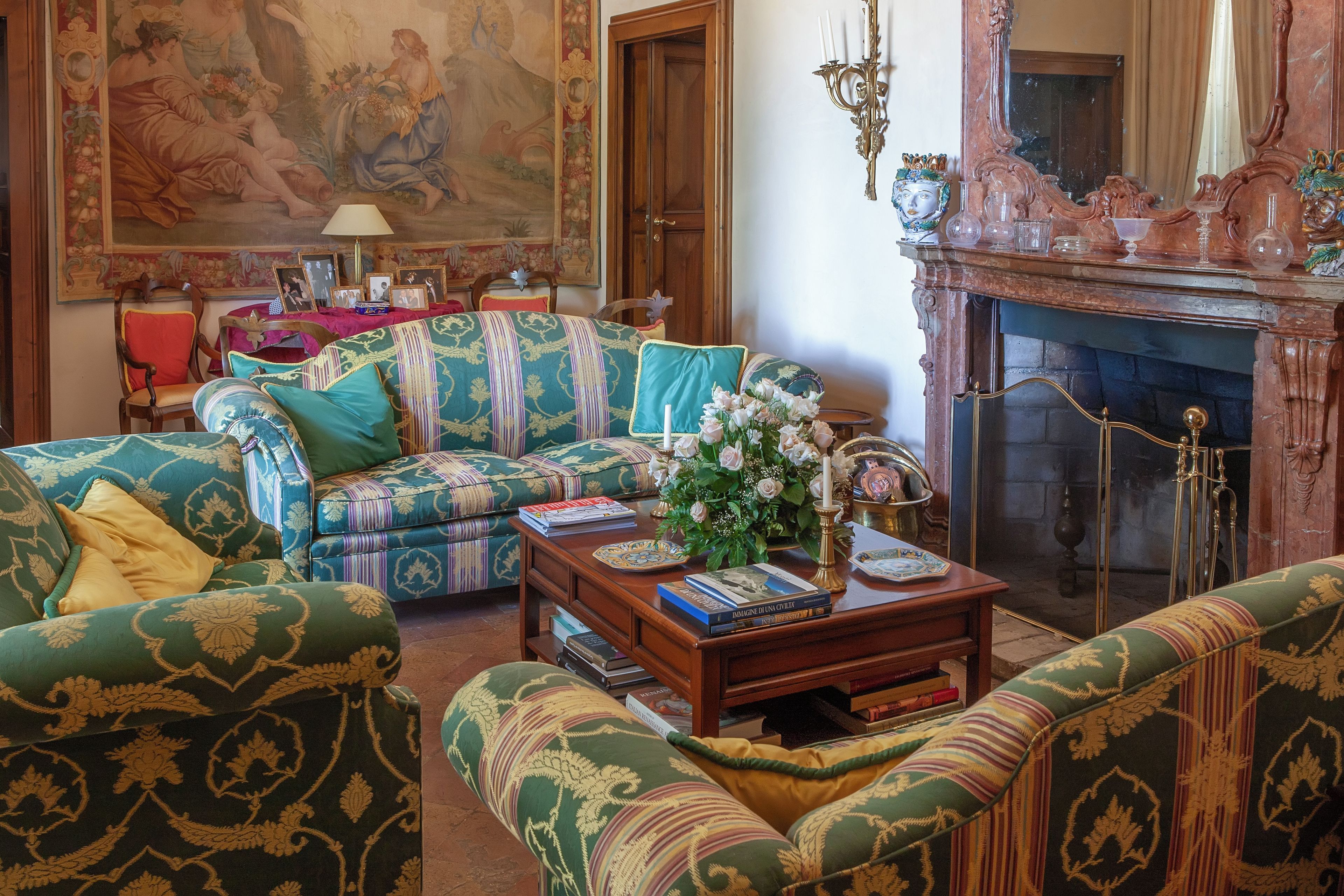 A traditional living room with patterned sofas, a fireplace, and a large painting on the wall.