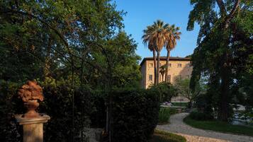 A building with a stone facade, surrounded by lush greenery and a gravel pathway.
