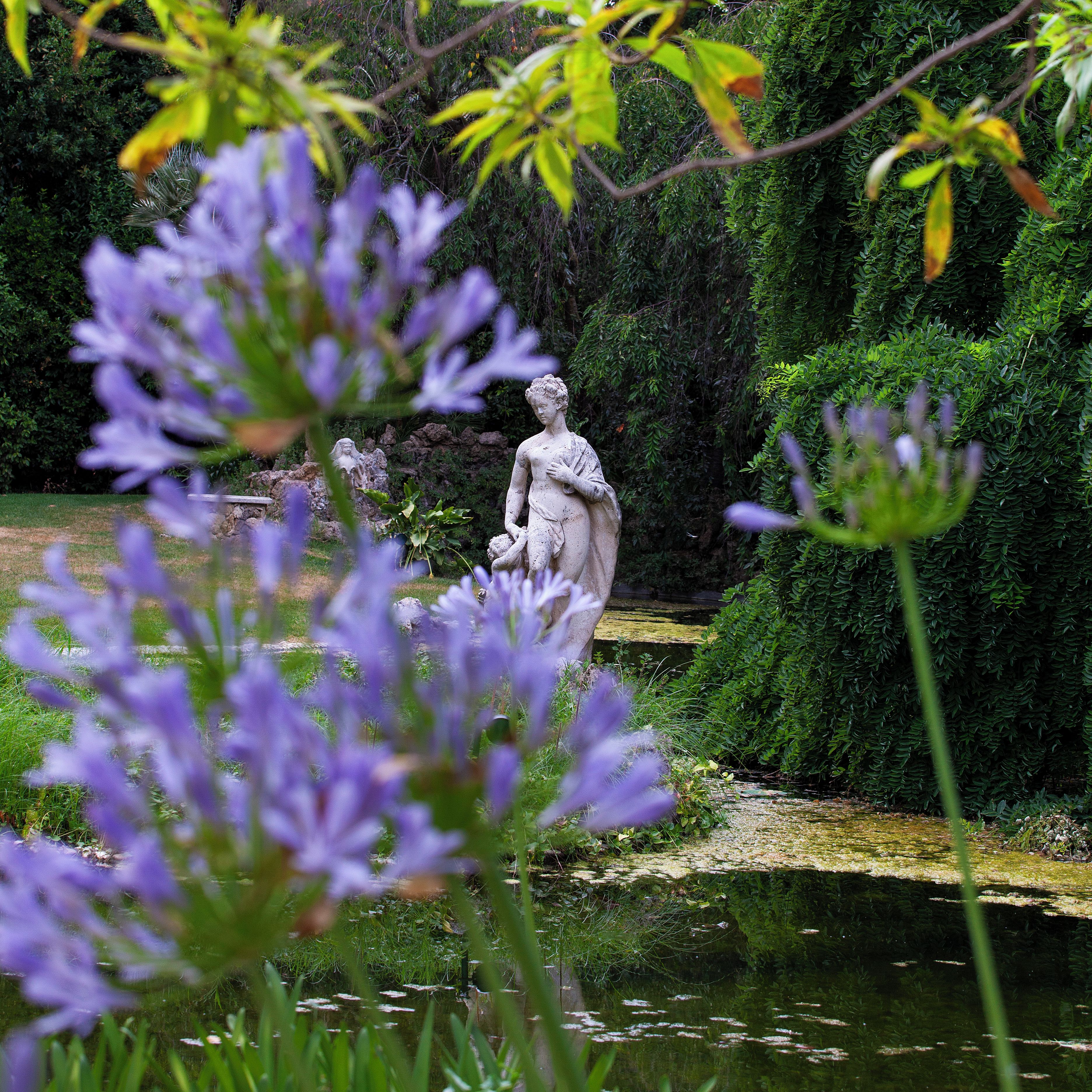 A garden with statues and a pond.