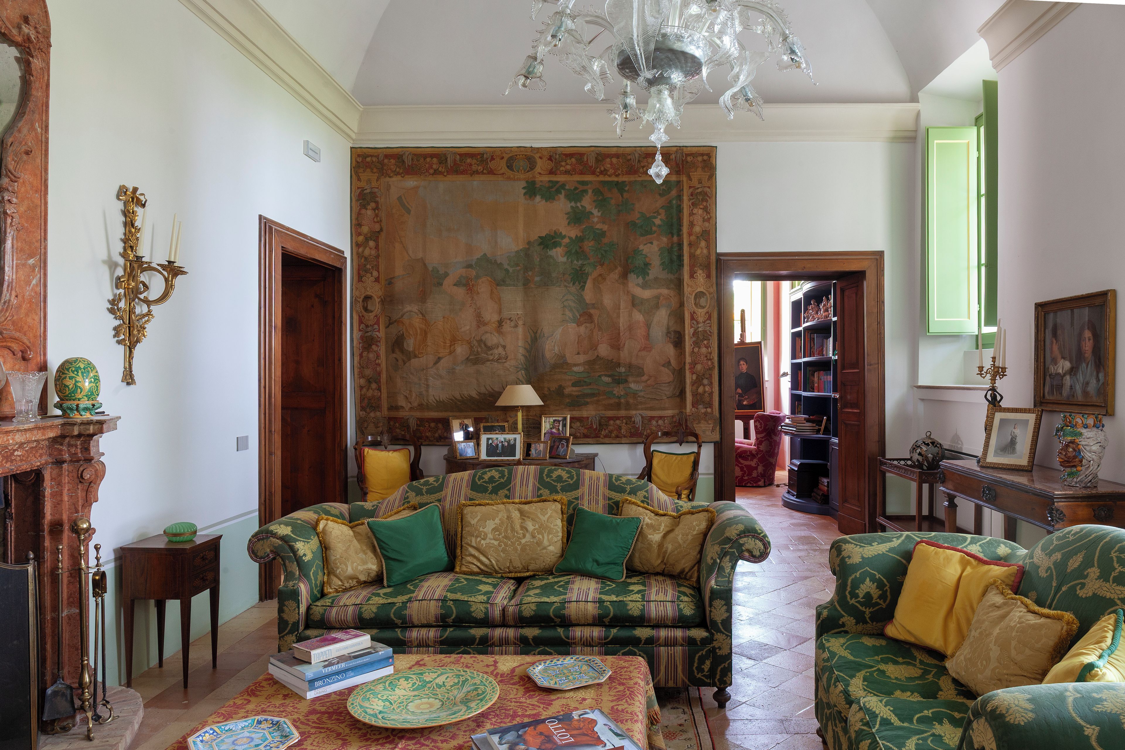 Ein traditionell eingerichtetes Wohnzimmer mit einem großen Wandteppich, einer Kristallleuchter und klassischen Möbeln.