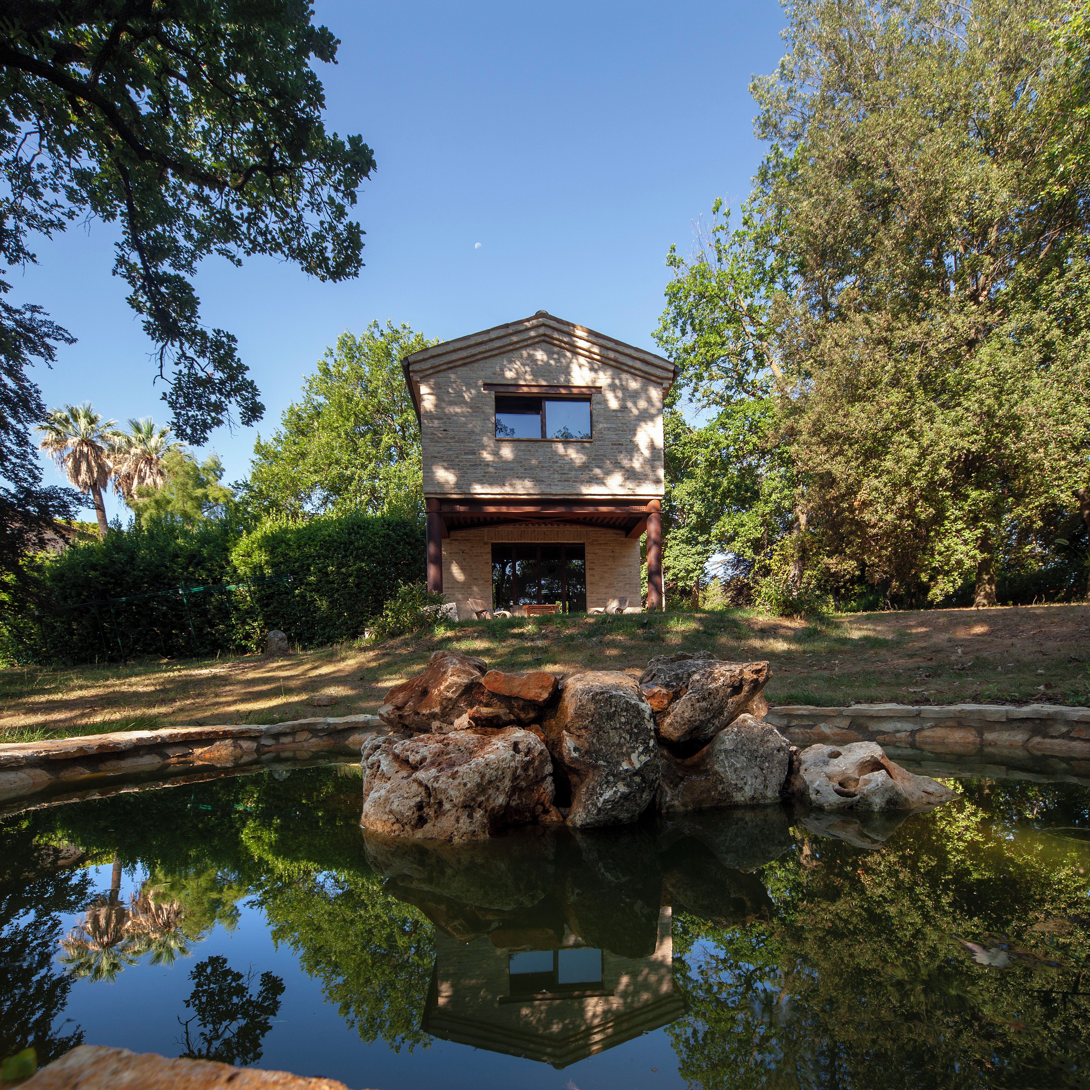 A building with a stone facade, a small window, and a pond in front.