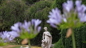 Uma estátua em um jardim com vegetação densa ao fundo.