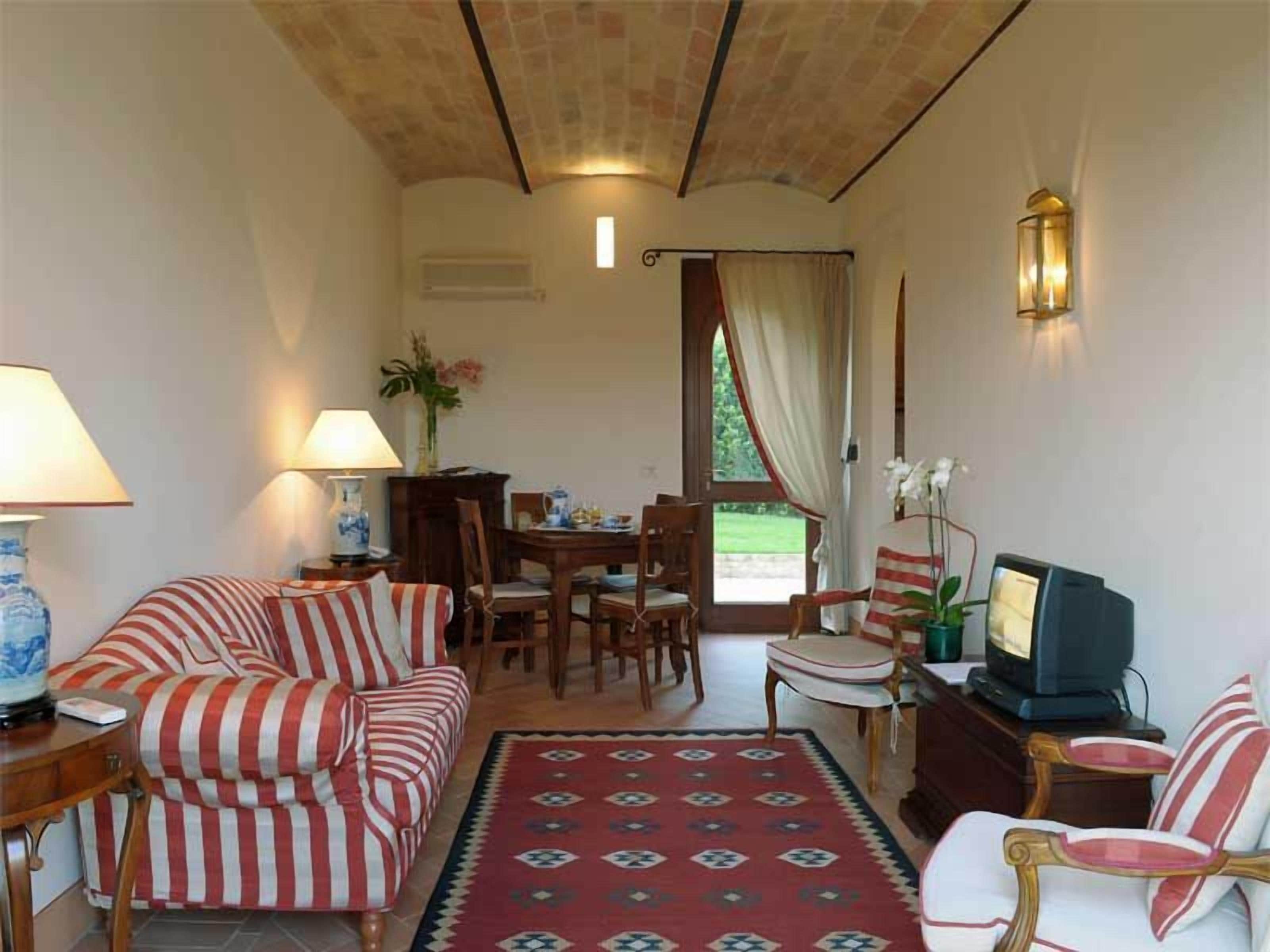 Una sala de estar con sofá, sillones, televisor y un comedor con mesa y sillas.