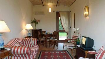 Una sala de estar con sofá, sillones, televisor y un comedor con mesa y sillas.