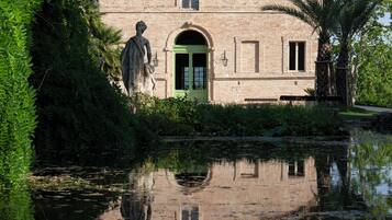 A historic building with a green door, a statue in front, and a reflection in the water.