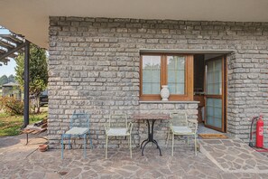 Un edificio de piedra con una ventana, dos sillas, una mesa y un extintor.