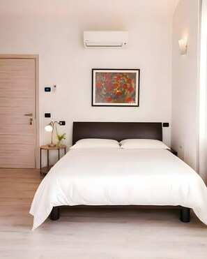 A modern bedroom with a bed, bedside table, lamp, air conditioning unit, and a framed artwork on the wall. - Apartment 'Villa Gabri 25 Wellness' with Wi-Fi and air conditioning (Seriate)