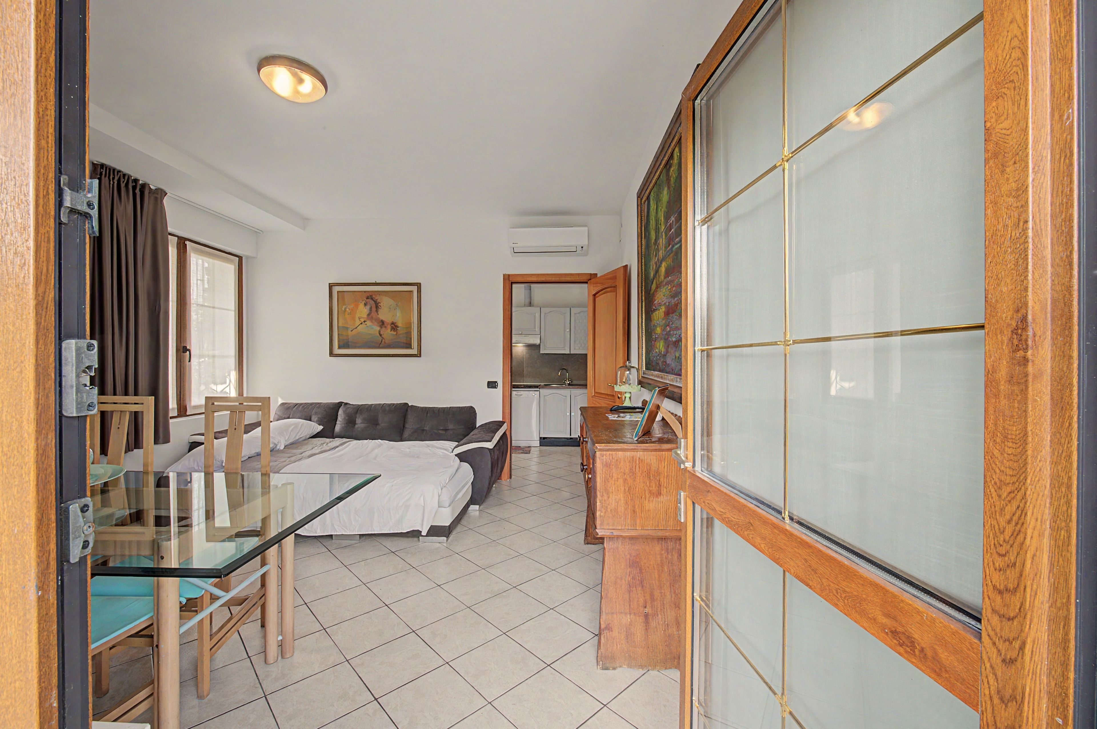 Ein Hotelzimmer mit einem Bett, einem Glastisch, einer Couch, einem Gemälde und einer Küchenzeile.