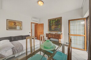 A bedroom with a bed, a dresser, a painting, and a door leading to another room.