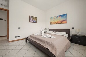 Une chambre d’hôtel avec un lit, une table de chevet, une lampe, un tableau et un climatiseur fixé au mur.