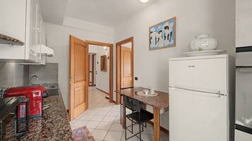 Una cocina con un tostador rojo, un refrigerador blanco y una puerta de madera que da a otra habitación.