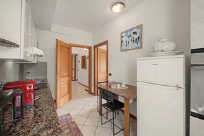 Une cuisine avec un grille-pain rouge, un réfrigérateur blanc et une porte en bois donnant sur une autre pièce.