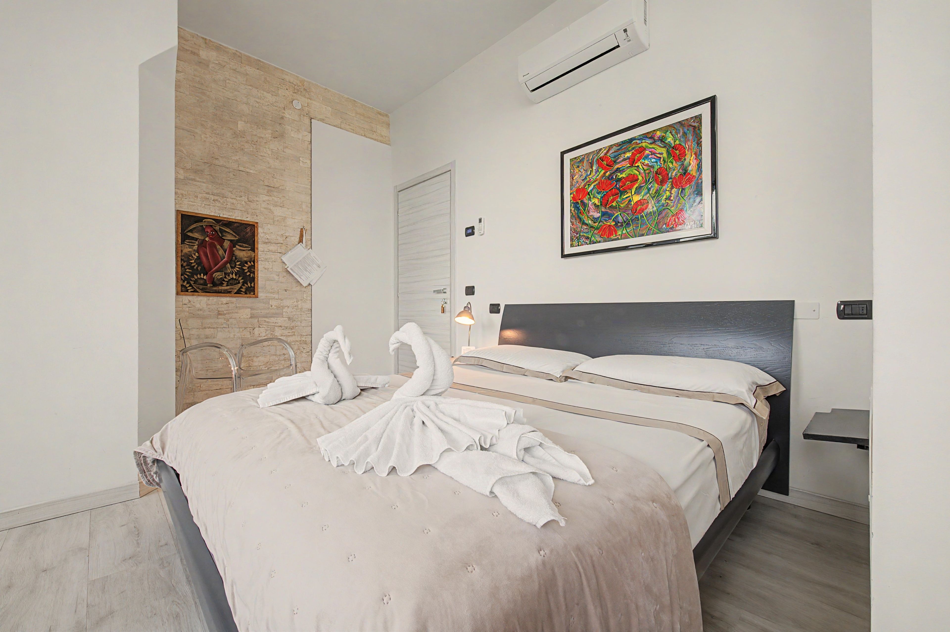 Una habitación de hotel con cama, un cuadro, un espejo y una puerta.