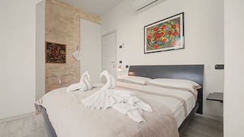 Una habitación de hotel con cama, un cuadro, un espejo y una puerta.
