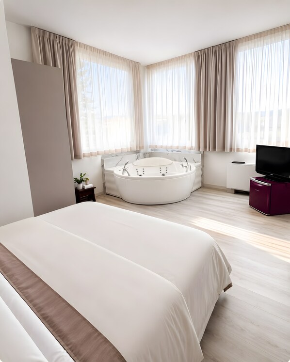 Une chambre d’hôtel moderne dotée d’un grand lit, d’un jacuzzi, d’une télévision et offrant une vue sur l’extérieur.
