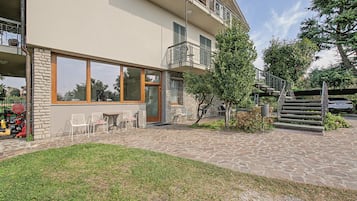 Een gebouw met een gevel van natuursteen, grote ramen, terras en een trap naar een hoger gelegen verdieping.