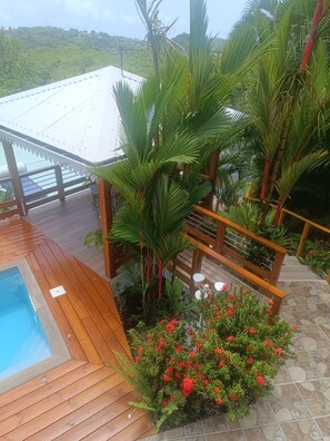 A wooden deck with a pool, surrounded by tropical plants and a stone-tiled area. - T -SYSSY LODGE  FOR 2 ADULTS (WITHOUT CHILDREN) TO DISCOVER MARTINIQUE (Fort-de-France)