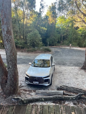 Een auto geparkeerd op een zandpad, omringd door bomen.
