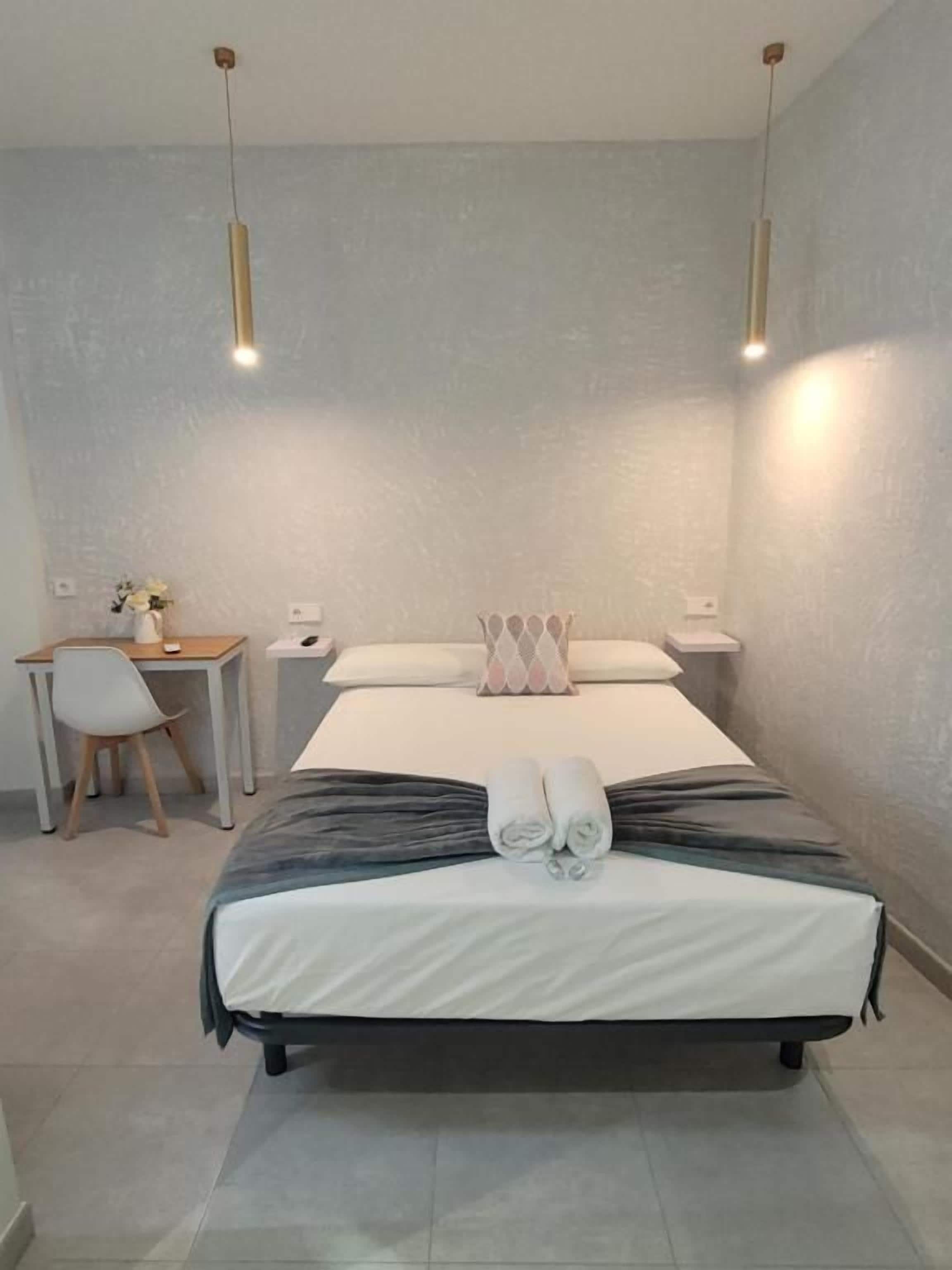Une chambre d’hôtel avec un lit, des tables de chevet, un bureau et une chaise.