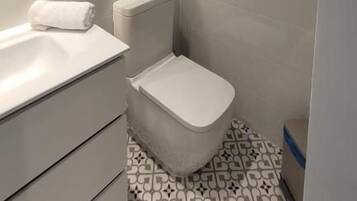 A bathroom with a toilet, bidet, and a sink.