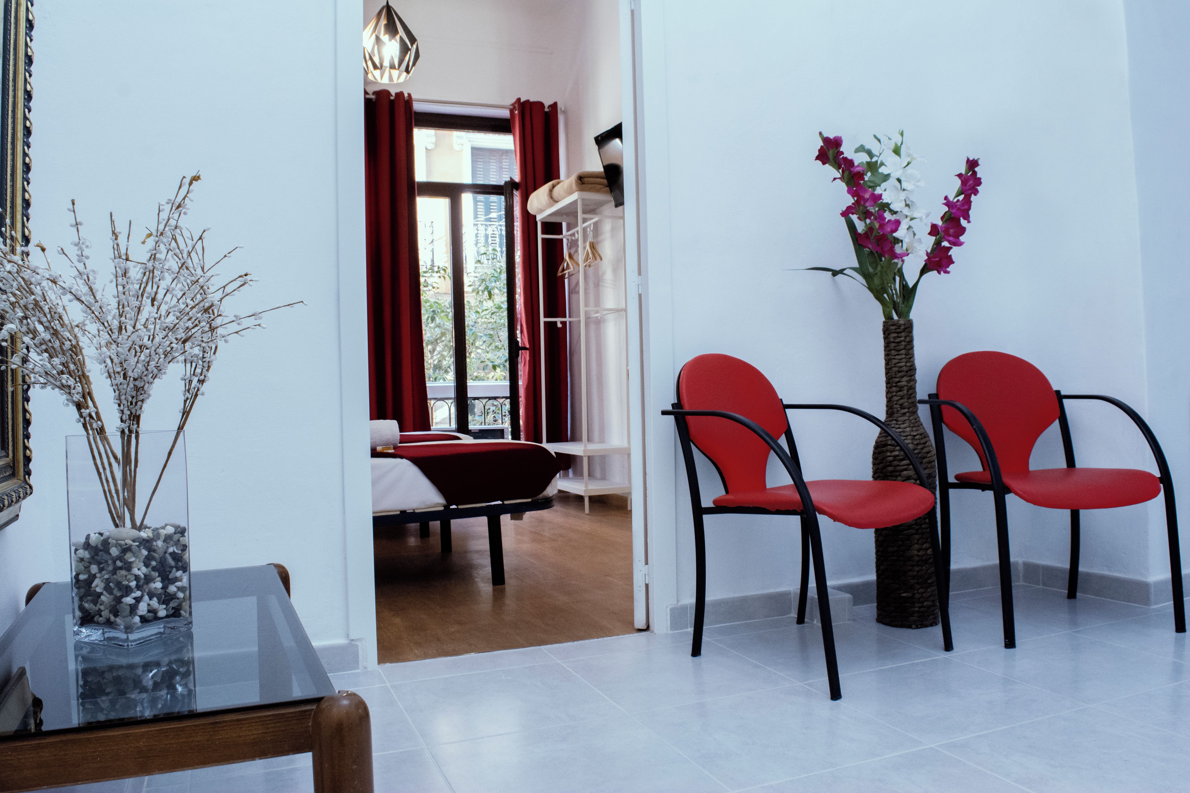 Een moderne hotelkamer met een eettafel, stoelen, een vaas met bloemen en uitzicht op het buiten.