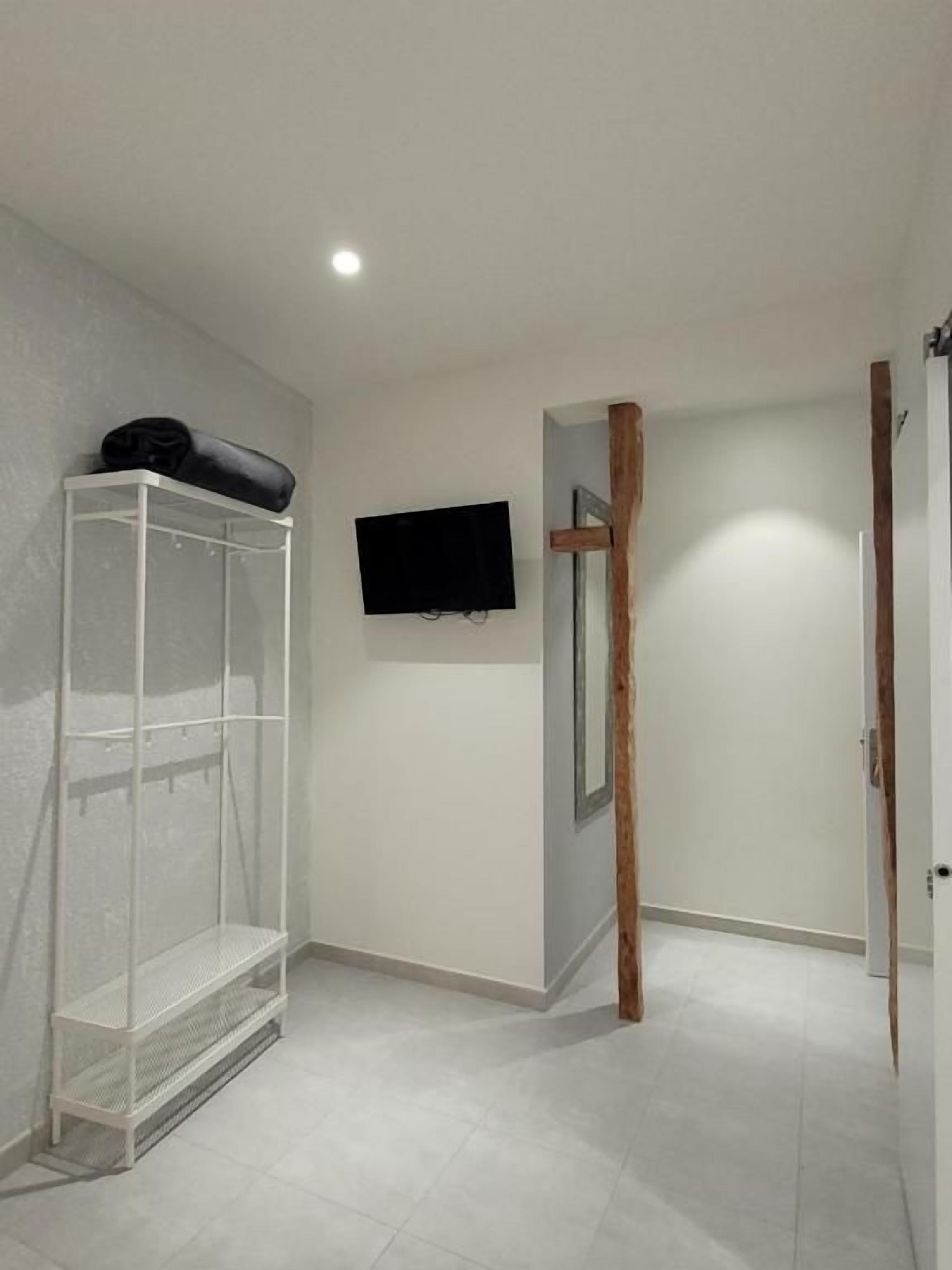 Una habitación con un estante blanco, un televisor montado y una puerta de madera.