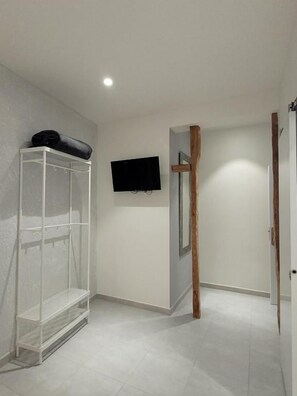 A room with a white shelving unit, a mounted television, and a wooden door. - Casa Lemus (Madrid)