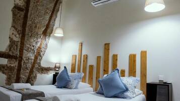 Une chambre d’hôtel avec deux lits, des têtes de lit en bois, un grand mur décoré avec un tronc d’arbre et une petite table de chevet avec une lampe.