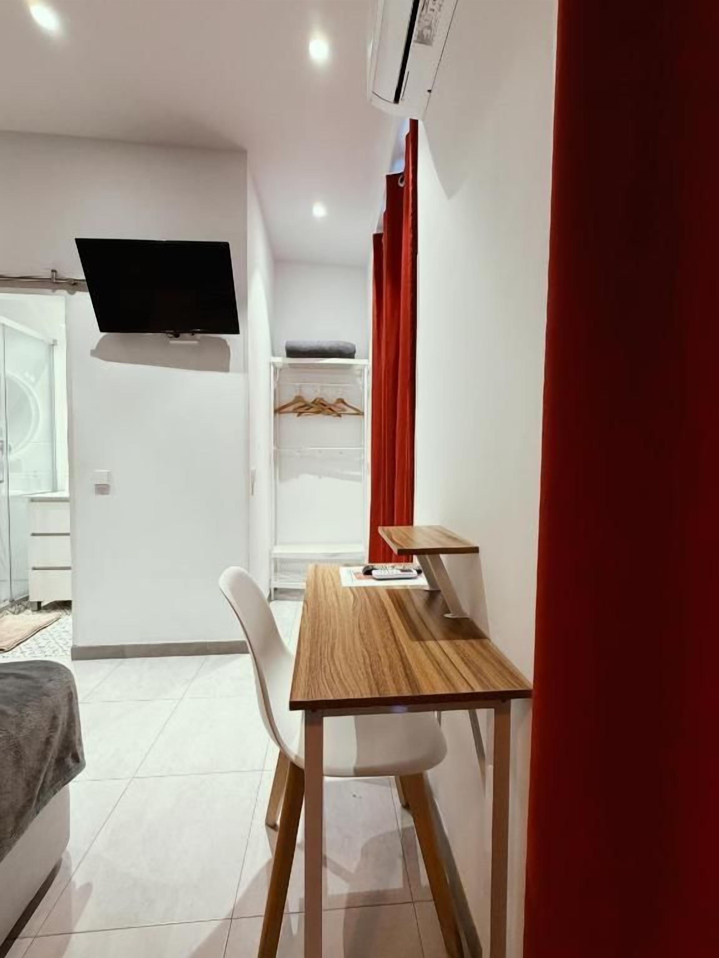 Una habitación moderna con una cama, un escritorio y un televisor montado en la pared.
