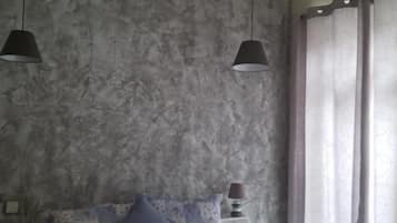 Un dormitorio con cama, mesitas de noche y una ventana con cortinas.
