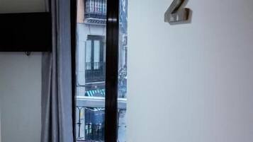 Une chambre avec un lit, une porte portant un numéro et une vue sur l’extérieur.