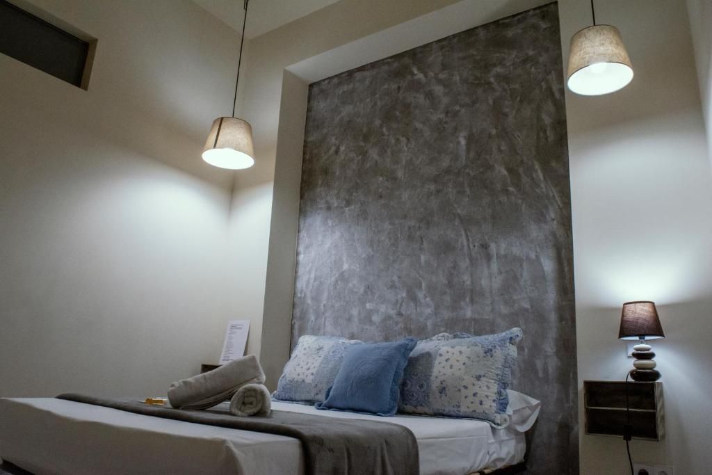 Een slaapkamer met een bed, twee bedlampen en een groot, gestructureerd wandpaneel.
