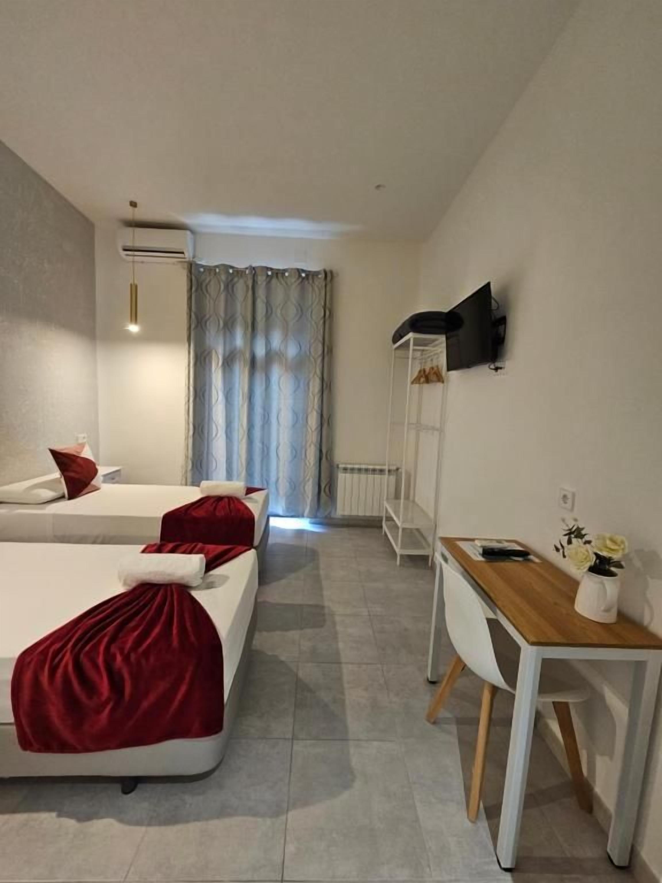 Een hotelkamer met een bed, een bureau en een stoel. Er is een raam met gordijnen.
