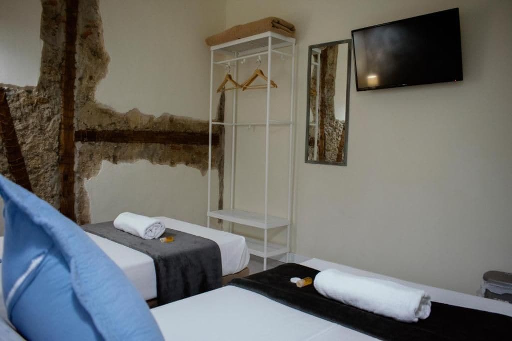 Habitación de hotel con dos camas, un armario, un televisor y un espejo.