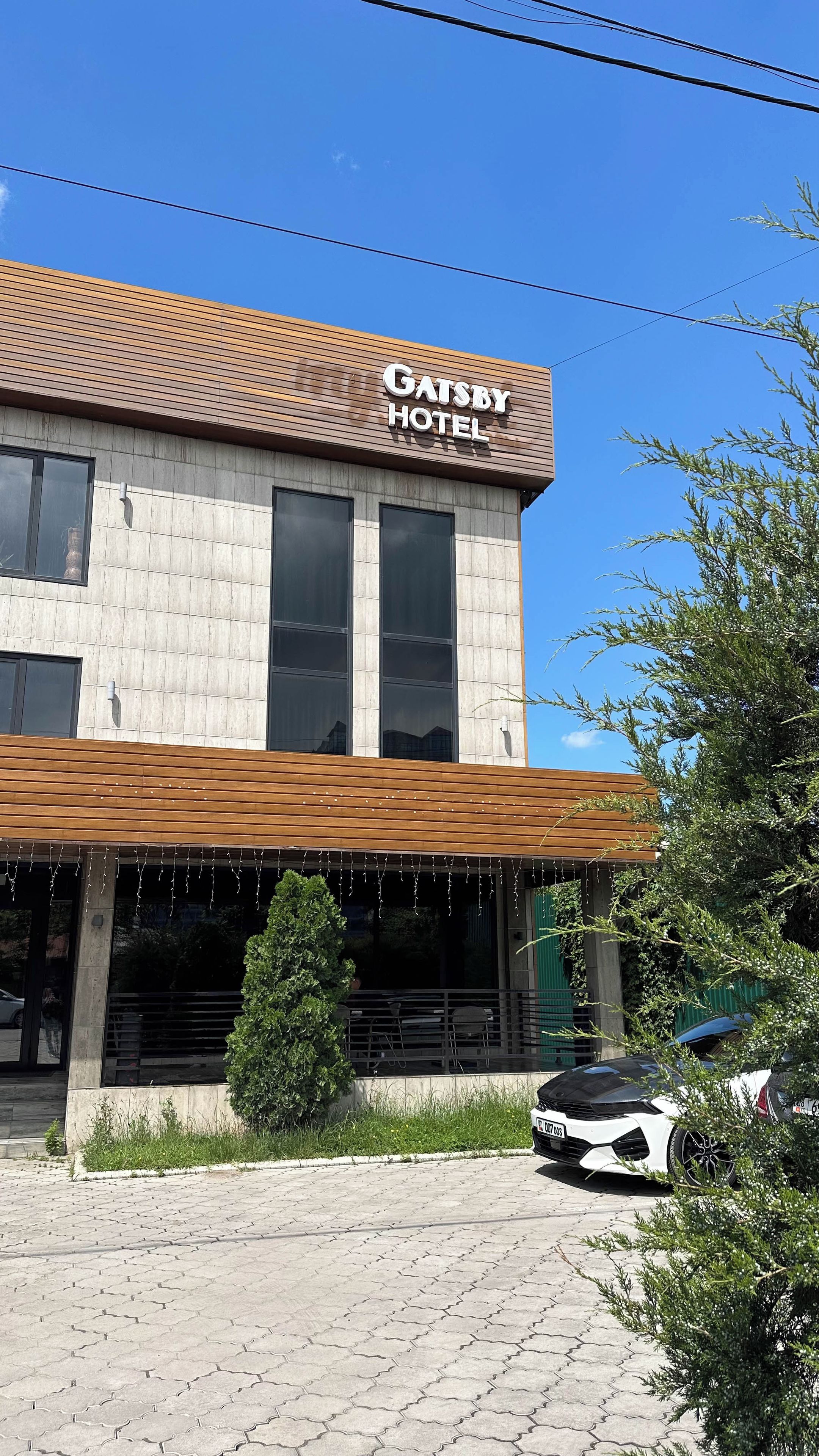 Un edificio con un cartel que dice 'Gatsby Hotel' y un área de entrada techada.