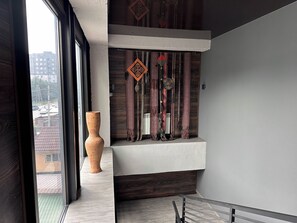 A modern interior with a large window, a decorative vase, and a wall-mounted shelf with patterned textiles. - Gatsby Vostok 5 (Bishkek)